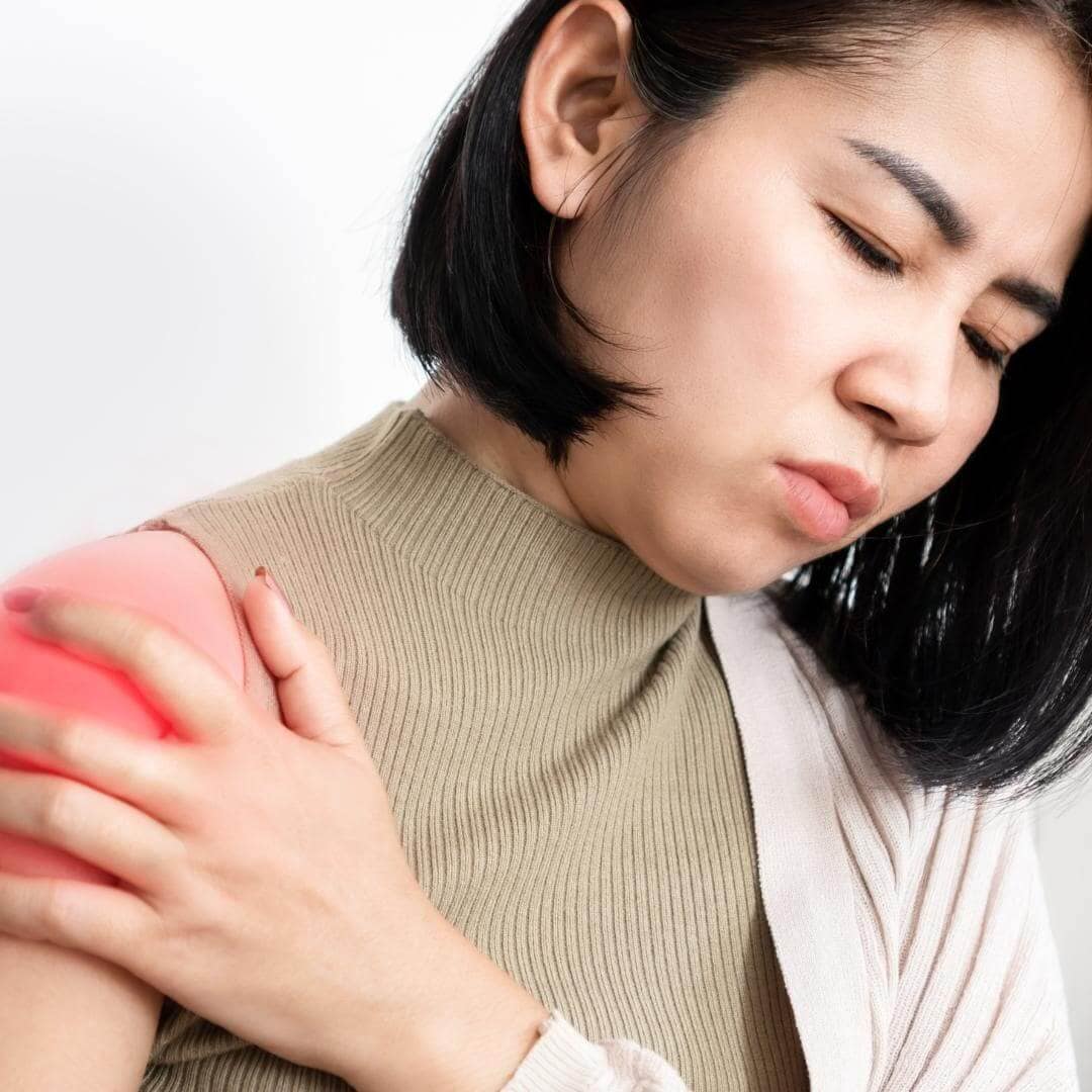 Photo of woman in holding her shoulder due to painful frozen shoulder.